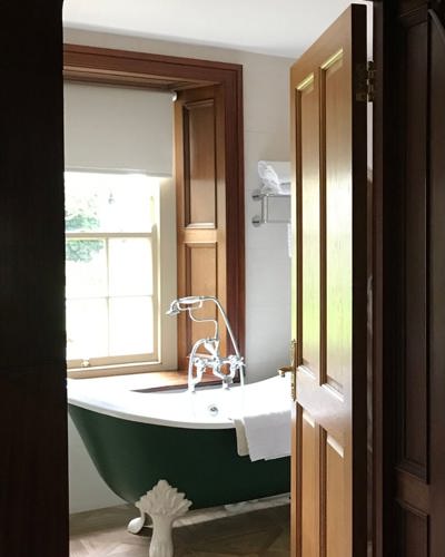 View through doorway of vintage hotel bathroom with wooden floors