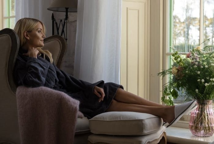 Woman relaxes in dressing down and slippers in armchair