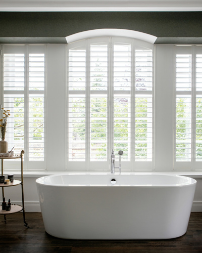 Large windows above a bathtub in bright hotel room