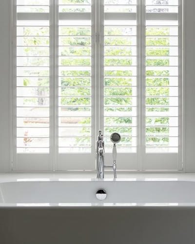 View of modern large white bath with large windows with garden views