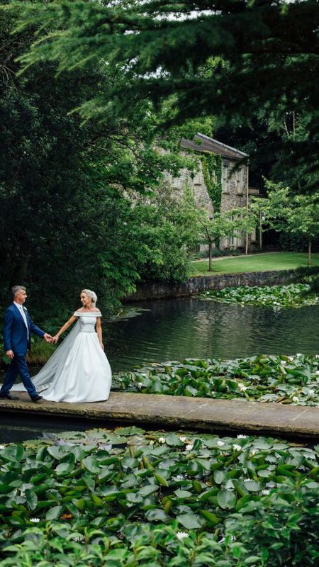 Bride leads groom over bridge in estate gardens near dublin