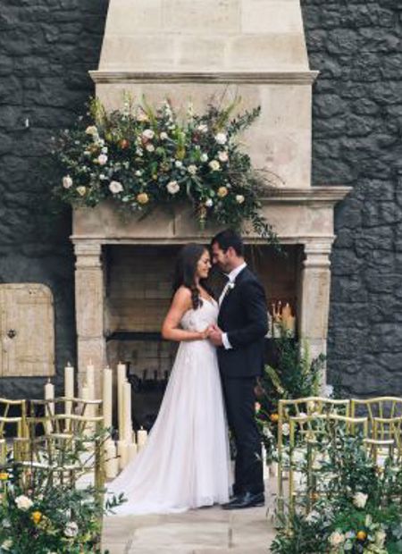 Couple pose on wedding day in front of fireplace on irish estate