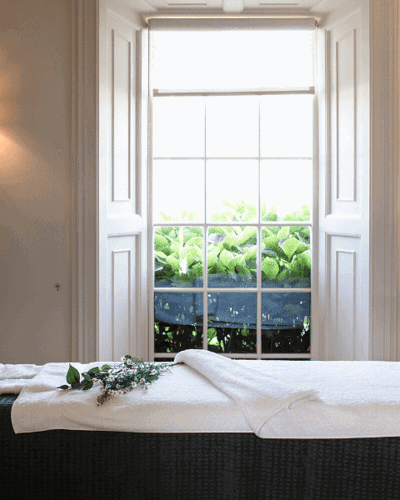 Massage table with flowers beside window with garden view