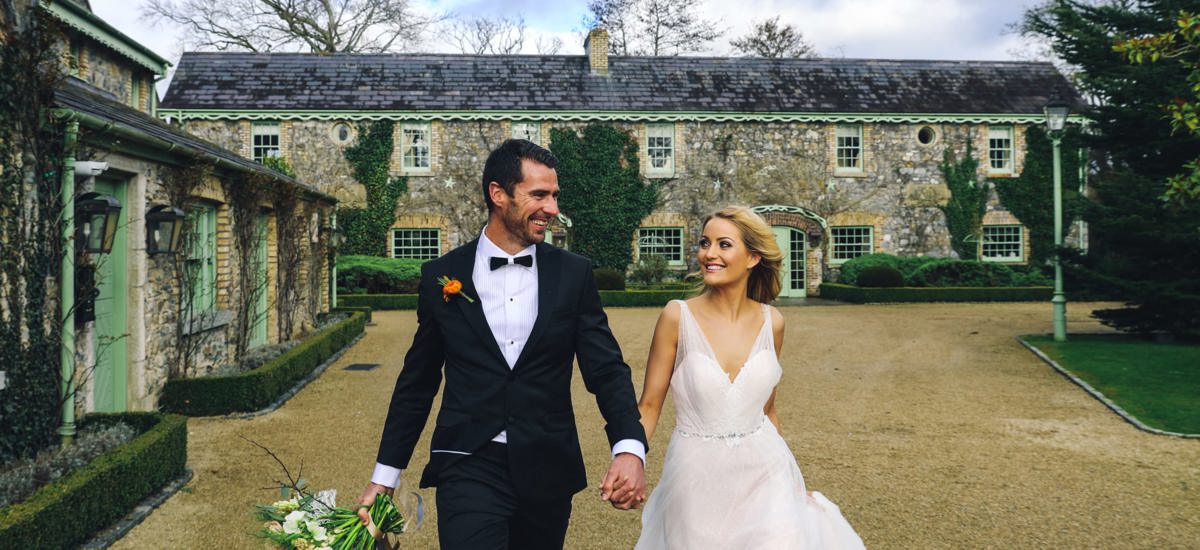 Bride and groom walk through country estate smiling